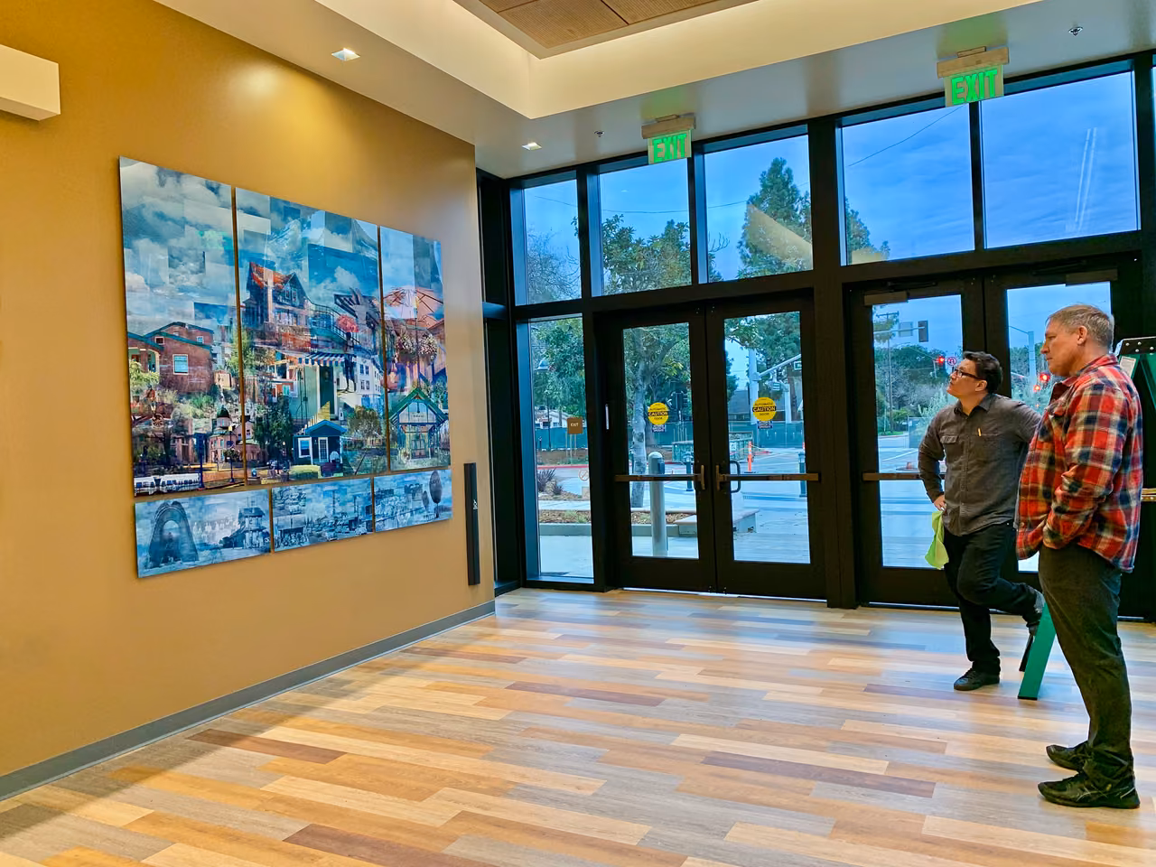 Two people looking at a large photographic mural on the wall of a community center lobby